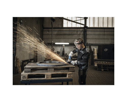 Mann mit Schutzbrille und Handschuhen schleift Metallring mit Winkelschleifer auf Palette, Funken fliegen