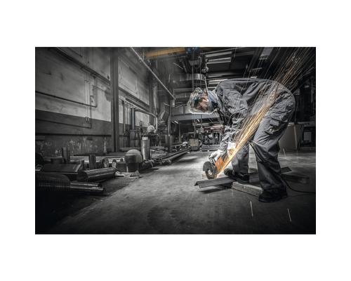 Un ouvrier travaille le métal avec une meuleuse d''angle dans un atelier.