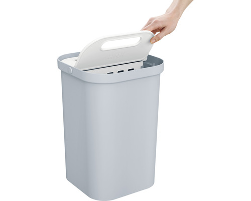 Poubelle avec couvercle ouvert par une main.