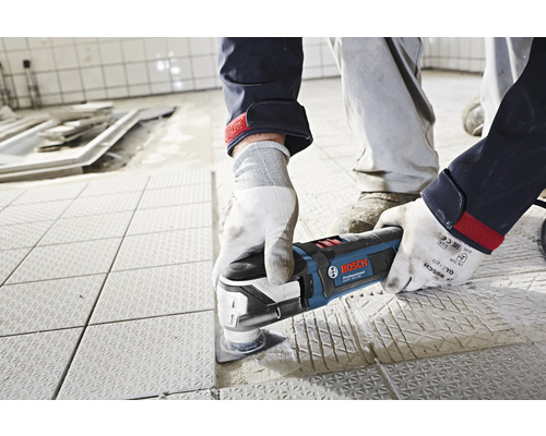 Artisan utilisant un outil multifonction Bosch sur des carreaux de sol.