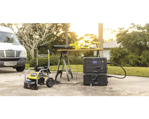 Ryobi Hochdruckreiniger, Laubbläser und Akku-Bohrschrauber zusammen mit einer Bluetti Powerstation auf einer Auffahrt.