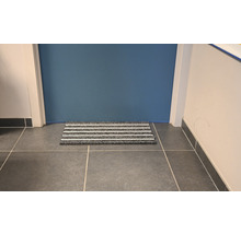 Fußmatte mit Streifen vor einer Tür auf Fliesenboden