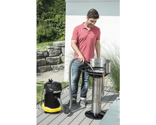 Mann reinigt einen Holzkohlegrill mit einem Aschesauger im Außenbereich