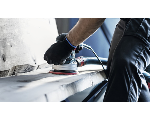 Une personne ponce du bois avec une ponceuse excentrique électrique.