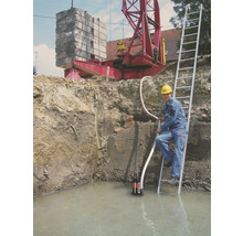 Fouille avec de l''eau, pompe submersible, ouvrier sur échelle et grue en arrière-plan