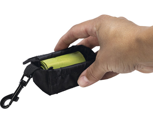 Une main tient un sac à déjections canines noir avec un mousqueton et un rouleau de sacs à déjections canines.