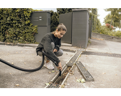 Femme nettoie une rigole avec un aspirateur eau et poussière.