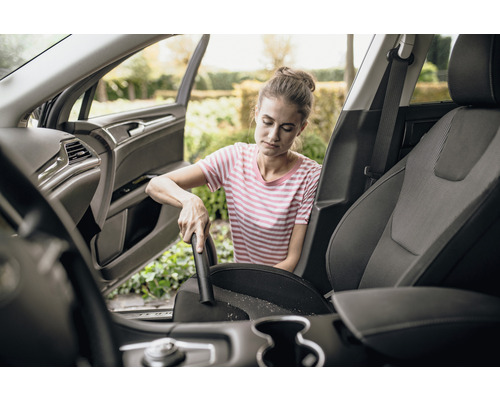Femme aspire l''intérieur de la voiture avec un aspirateur