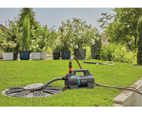 Garten Szene mit einer Gardena Gartenpumpe verbunden mit einem Wasserschacht und einem Rasensprenger