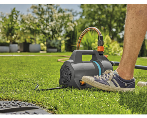 Gartenpumpe mit Schlauch auf Rasen im Garten