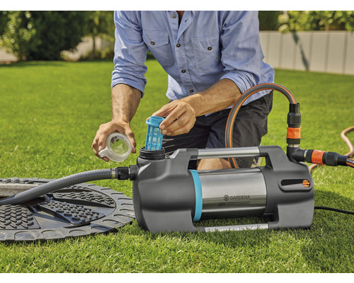 Gartenpumpe beim Einsetzen des Filters auf einer Rasenfläche