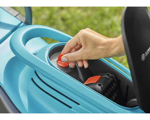 Hand betätigt roten Knopf an einem Rasenmäher