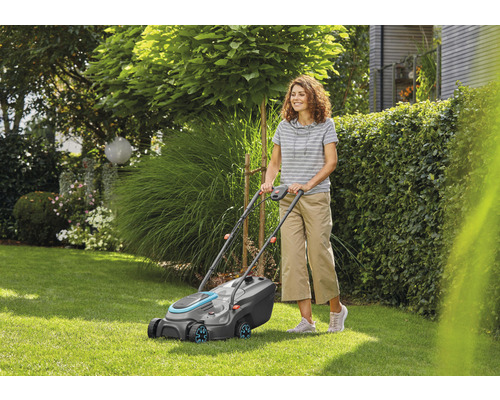 Frau benutzt Rasenmäher im Garten.