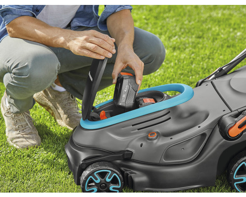 Mann setzt Akku in Rasenmäher ein