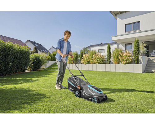 Mann mäht Rasen mit einem Gardena Rasenmäher im Garten.