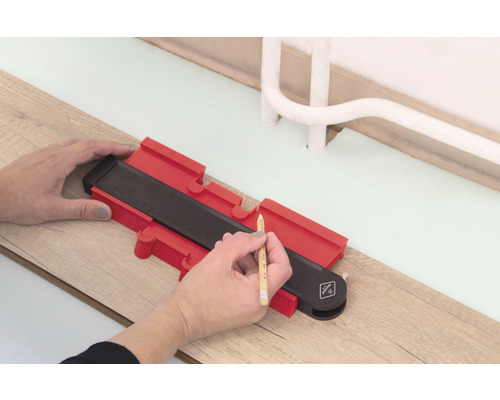 Person verwendet eine Konturenlehre zum Anzeichnen auf einem Holzboden