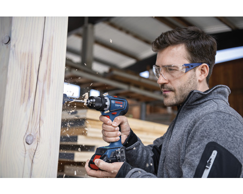 Mann bohrt mit Akku-Bohrschrauber in Holz
