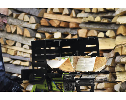Fendeuse de bûches avec des bûches devant une pile de bois