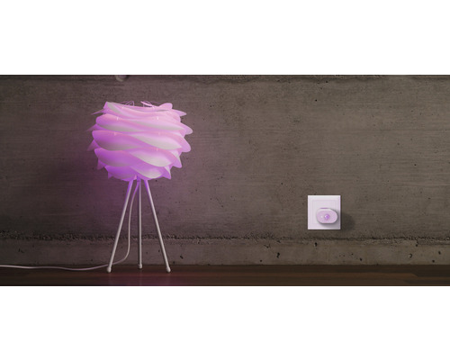 Lampe de table décorative avec abat-jour et cadre à trois pieds à côté d''une prise murale.