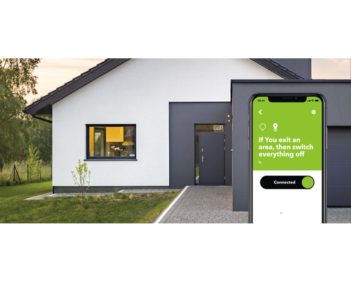 Smartphone mit Smart Home App vor einem Wohnhaus.