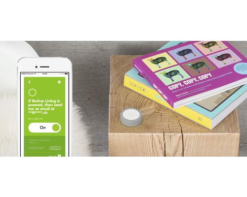 Smartphone avec application à côté d''un bouton et de livres sur un tabouret en bois