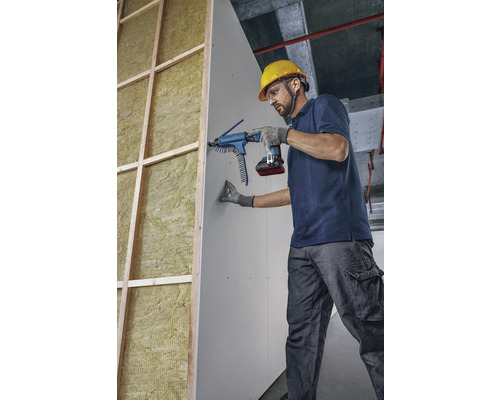 Un artisan fixe une plaque de plâtre sur un mur à l''aide d''une visseuse à magasin.