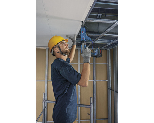 Un homme fixe une plaque de plâtre au plafond à l''aide d''une visseuse pour plaques de plâtre.