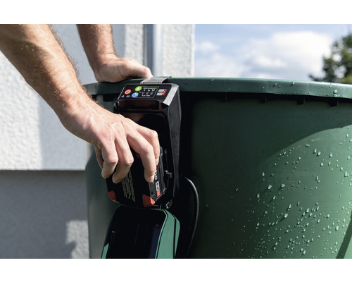 Mann setzt Akku in eine Regenfasspumpe ein.