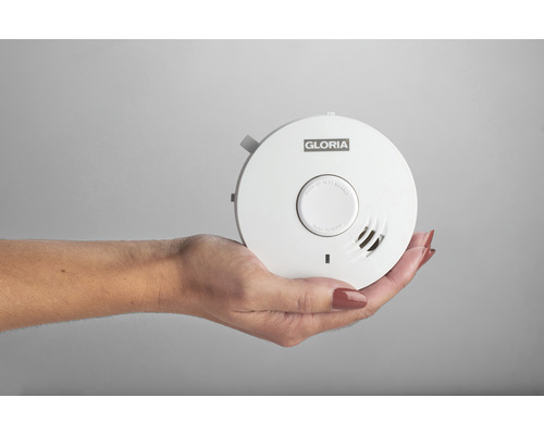 Une main tient un détecteur de fumée Gloria.
