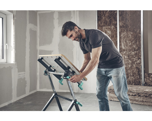 Un homme travaille sur un établi Wolfcraft dans une pièce non rénovée.