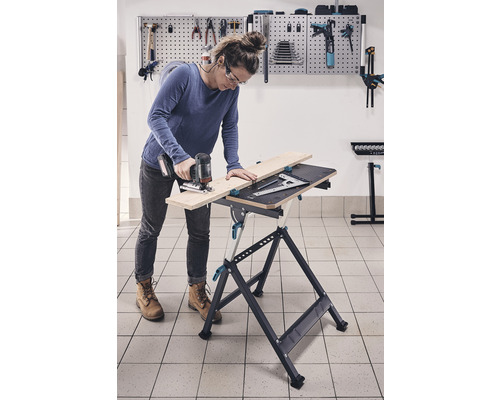 Une femme travaille avec une scie sauteuse sur un établi dans un atelier.