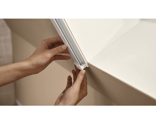 Installation einer Gardinenschiene an der Decke durch eine Person.