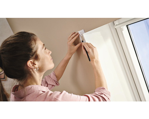 Frau markiert Position für Fensterdekoration an Wand