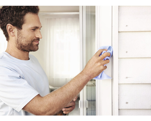 Mann reinigt Fensterrahmen mit einem Tuch