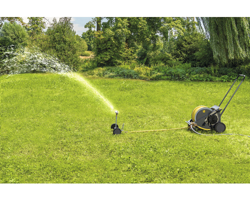 Scène de jardin avec arroseur de pelouse et dévidoir en marche