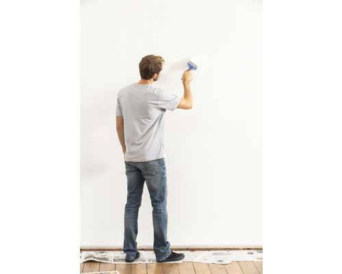 Mann streicht eine Wand mit einem Pinsel
