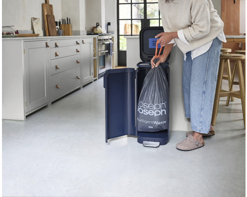 Femme remplaçant un sac poubelle dans une poubelle Joseph Joseph IntelligentWaste Titan dans une cuisine