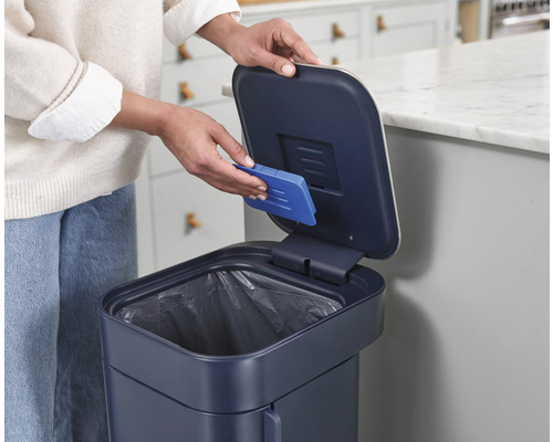 Une personne remplace le filtre anti-odeurs d''une poubelle.