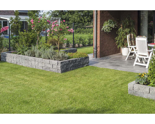 Garten mit Rasen, Hochbeet aus Steinen und Terrasse mit Gartenmöbeln