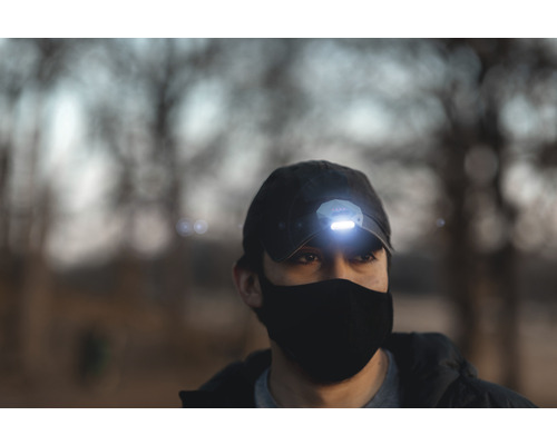 Person mit Stirnlampe auf einer Kappe und Gesichtsmaske.