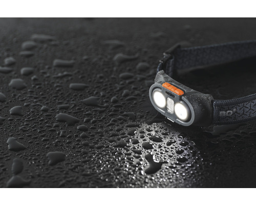 Stirnlampe mit eingeschaltetem Licht auf dunkler Oberfläche