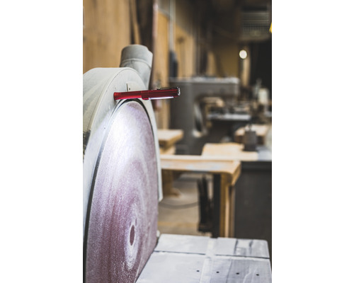 Eine Schleifmaschine mit einer roten Stablampe, die daran befestigt ist.