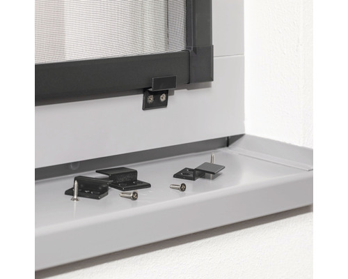 Detailansicht eines Insektenschutzfensters mit Montagezubehör und Schrauben auf einer Fensterbank.