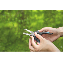 Gartenschere in Händen vor grünem Hintergrund