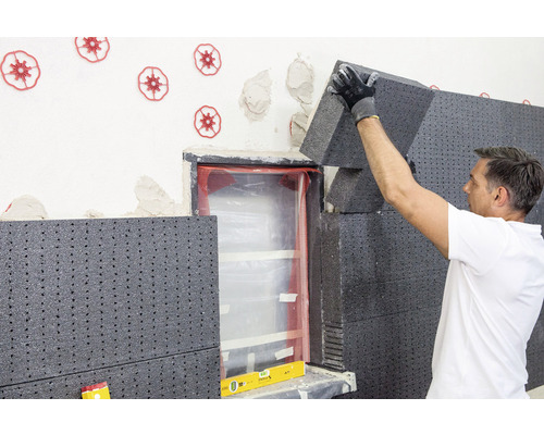 Un homme pose une isolation thermique sur un mur