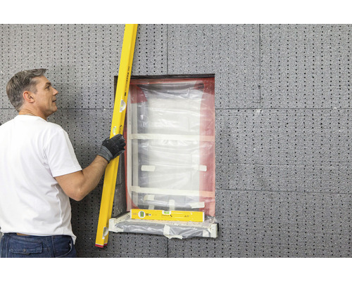 Homme utilisant un niveau à bulle sur l''embrasure d''une fenêtre avec des panneaux d''isolation thermique
