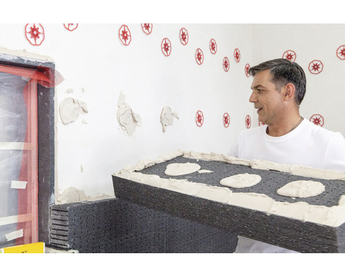 Un homme travaille un panneau isolant sur un mur