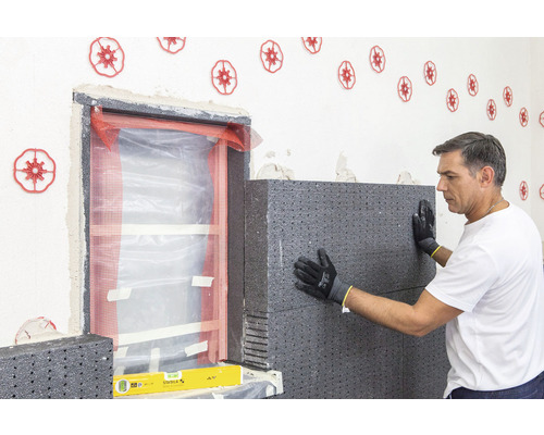 Artisan fixant des panneaux isolants sur le mur extérieur