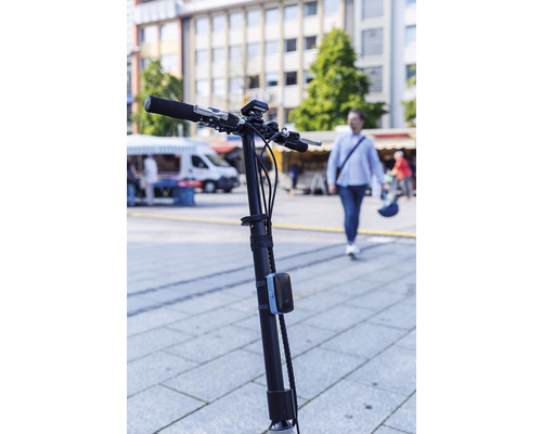 Guidon et potence d''une trottinette électrique devant un paysage urbain animé