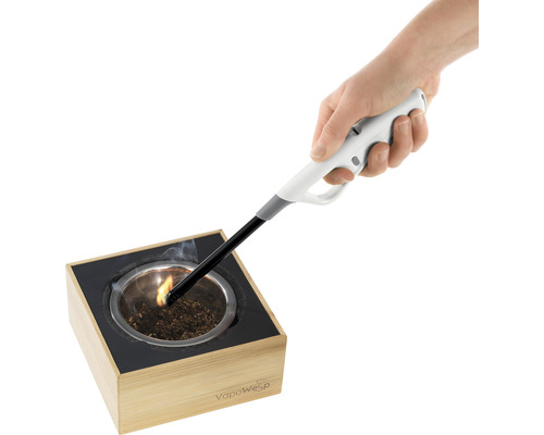 Eine Hand hält ein Stabfeuerzeug über ein Räuchergefäß, in dem Räucherstäbchen brennen